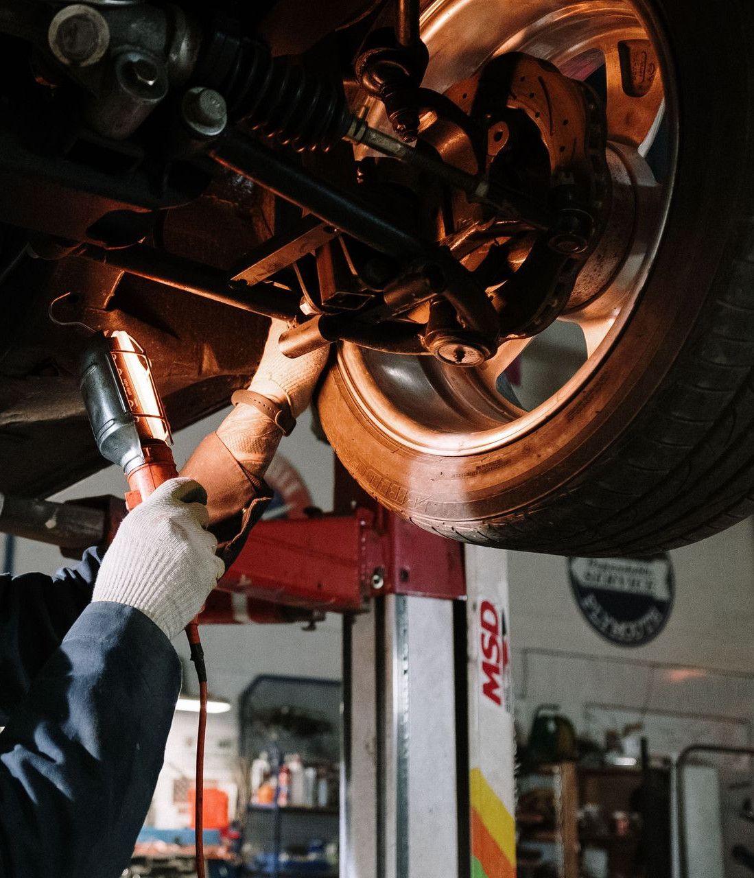 Mechanic examining car's undercarriage at a garage, focusing on vehicle maintenance.