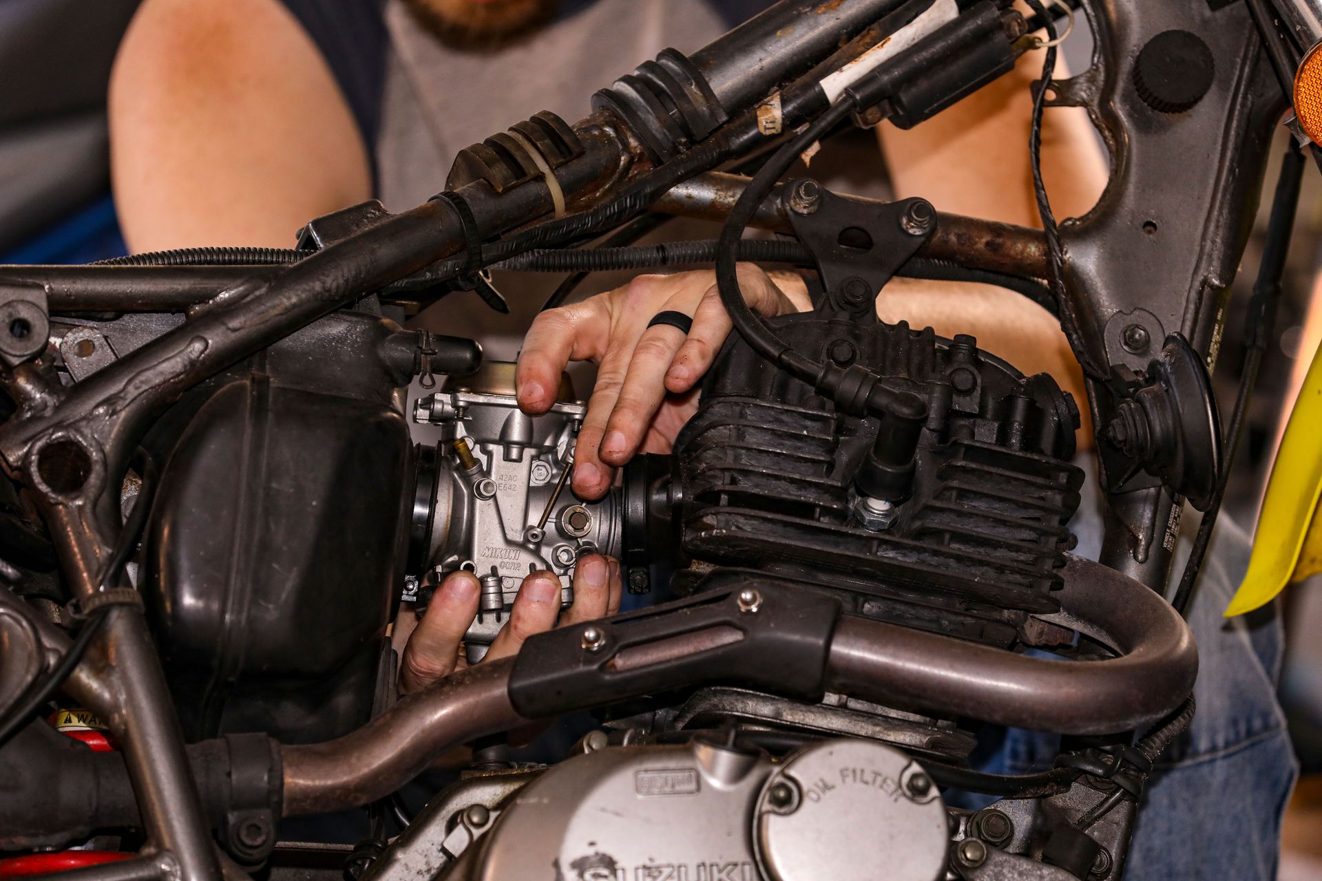 Mechanic skillfully repairs motorcycle engine, showcasing hands-on expertise.
